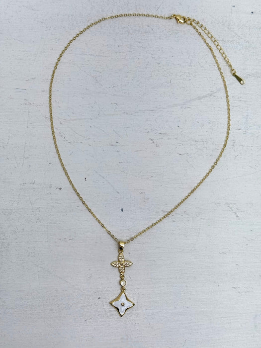 elegant gold necklace with crystal cross detail and enamel on a light gray background