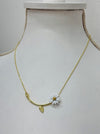 A gold-colored necklace with a daisy flower pendant and a tiny leaf detail, displayed on a mannequin.