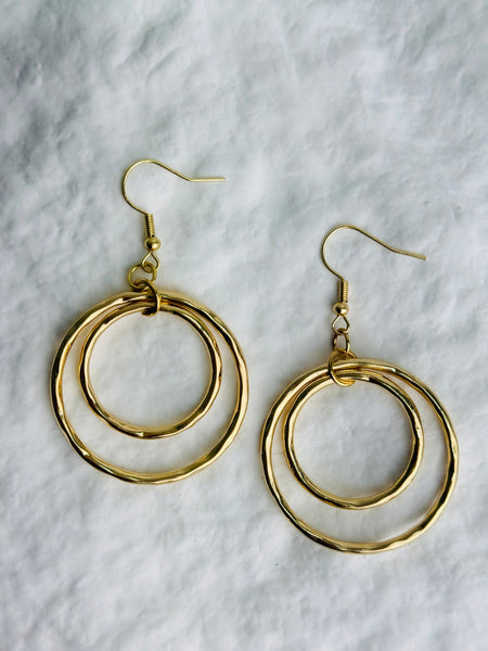 Gold hoop earrings on a textured white background