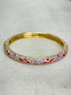 Gold bangle with red accents on a white background