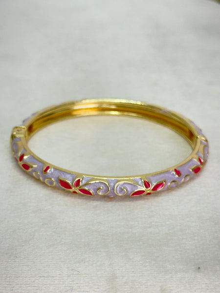 Gold bangle with red accents on a white background