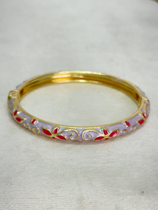 Gold bangle with red accents on a white background