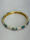 Gold bracelet with blue and white patterns on a light gray background