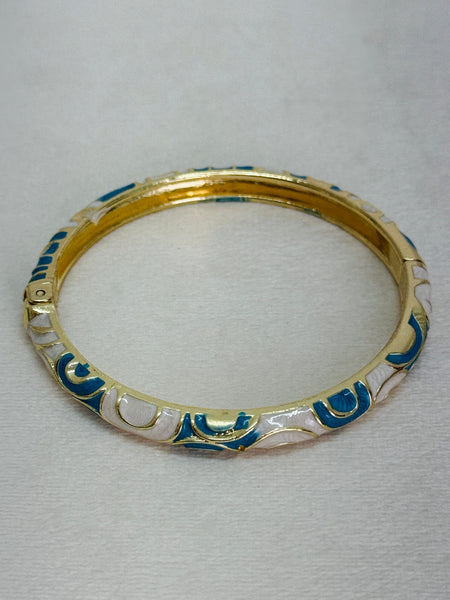 Gold bracelet with blue and white patterns on a light gray background