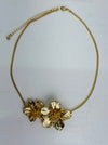 Gold floral necklace on a light gray background