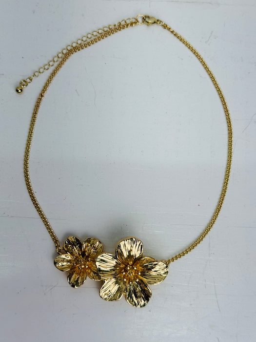 Gold floral necklace on a light gray background