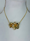 Gold floral necklace on a mannequin bust against a white background