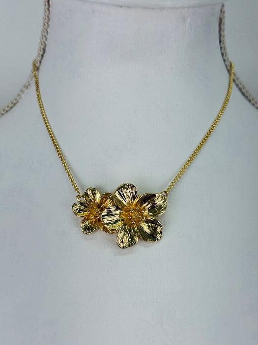 Gold floral necklace on a mannequin bust against a white background