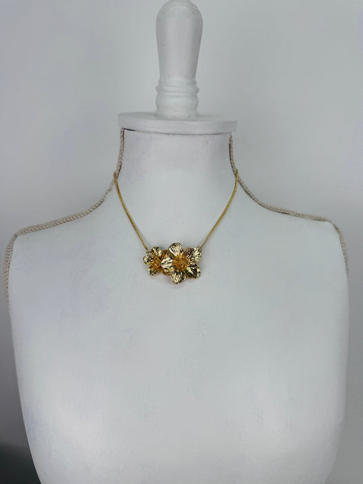 Gold necklace on a mannequin bust against a white background