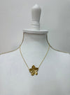 A gold-coloured necklace with a floral detail pendant, displayed on a mannequin
