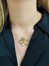 A gold-coloured necklace with a floral detail pendant, displayed on a model