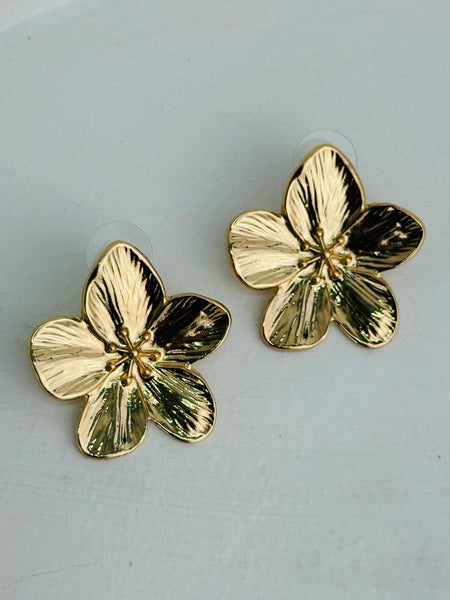 Gold flower-shaped earrings on a light gray background