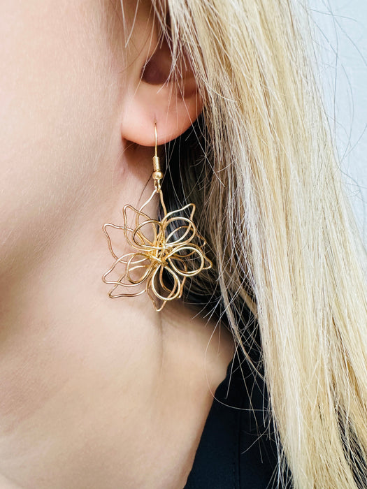 A close-up of a gold-coloured floral design dangle earring.
