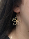 Gold flower-shaped earring displayed on a model