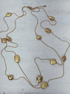 Long gold necklace with textured geometric charms displayed on mannequin