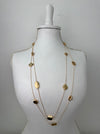 Long gold necklace with textured geometric charms displayed on mannequin