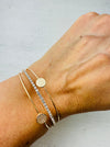 Close-up of a wrist wearing gold bracelets with a light background