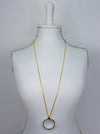 Gold magnifying glass pendant necklace with round glass lens on a gold chain.