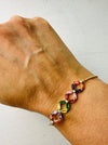 A multicolored beaded bracelet with gold-colored metal spacers and closures, worn on a wrist.