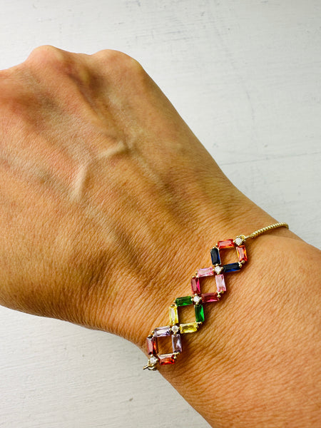 A multicolored beaded bracelet with gold-colored metal spacers and closures, worn on a wrist.
