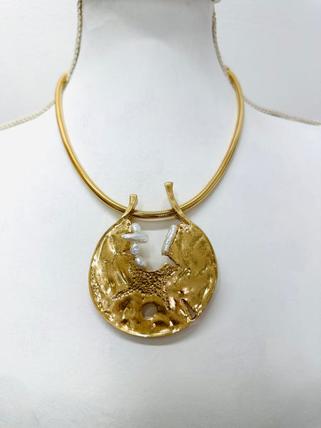 Gold necklace with a round pendant on a mannequin