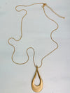 aerial view of gold necklace with a long chain and a teardrop-shaped metal pendant
