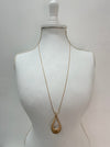 gold necklace with a long chain and a teardrop-shaped metal pendant displayed on a mannequin