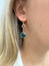 Elegant gold drop earrings with pink crystal and deep blue teardrop stone on a model