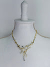 Gold and silver-tone abstract necklace with interwoven curved bars and adjustable chain on white background.