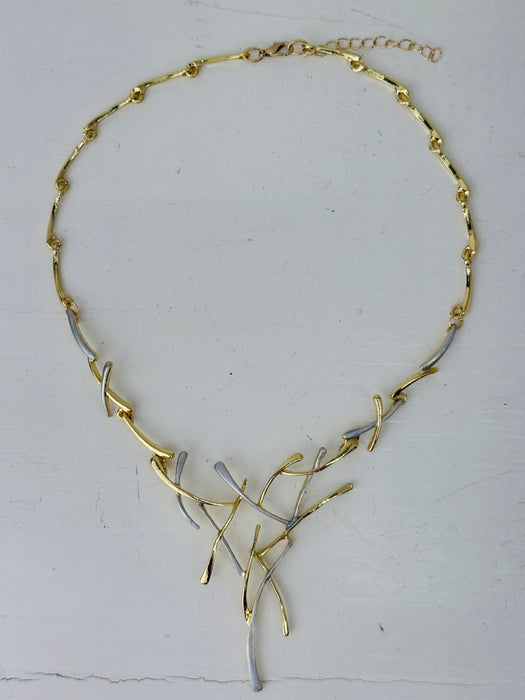 Gold and silver-tone abstract necklace with interwoven curved bars and adjustable chain on white background.