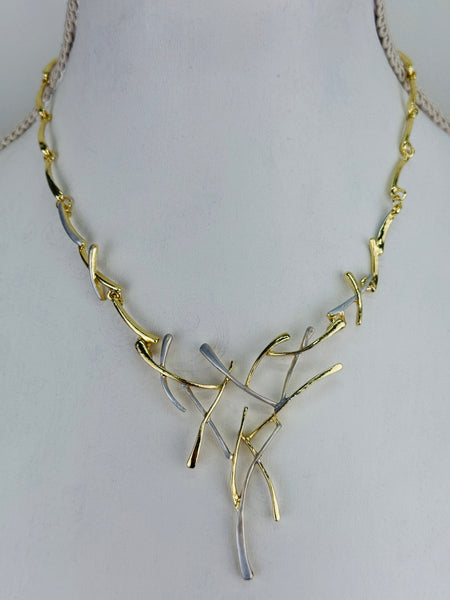 Gold and silver-tone abstract necklace with interwoven curved bars and adjustable chain on white background.