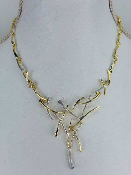 Gold and silver-tone abstract necklace with interwoven curved bars and adjustable chain on white background.