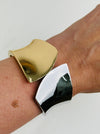 Gold and silver tone cuff bracelet with sculptural leaf shape and polished finish displayed on a model.