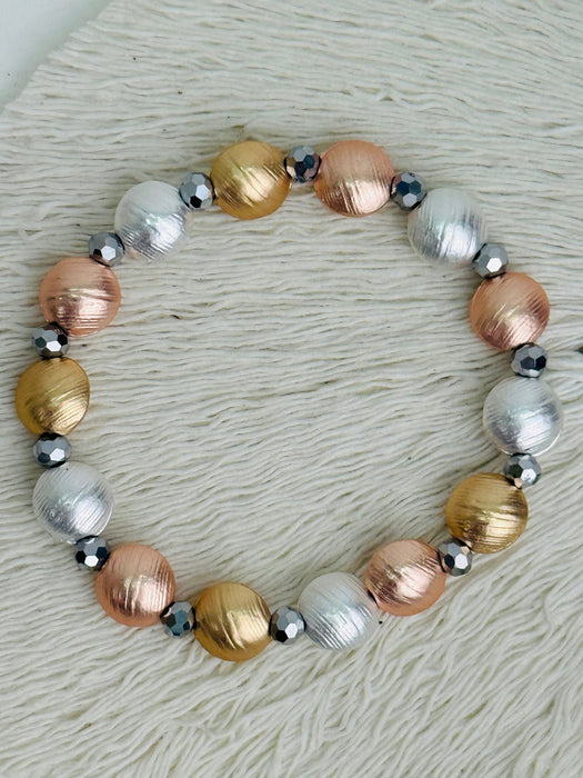 Tri-tone metallic beaded elastic bracelet in gold, silver and rose gold tones with grey spacer beads displayed on a white background.