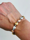 Tri-tone metallic beaded elastic bracelet in gold, silver and rose gold tones with grey spacer beads, displayed on a model.