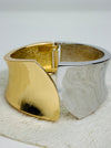 Gold and silver tone cuff bracelet with sculptural leaf shape and polished finish.