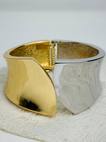 Gold and silver tone cuff bracelet with sculptural leaf shape and polished finish.
