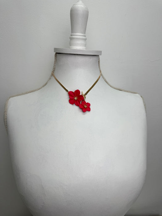 Red floral earring on a white bust against a gray background