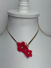 close-up of gold necklace with red floral pendants on a white mannequin bust.