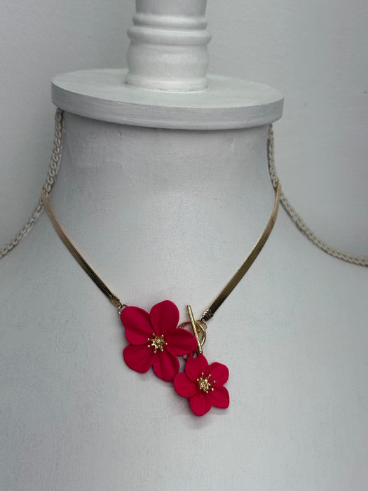 close-up of gold necklace with red floral pendants on a white mannequin bust.