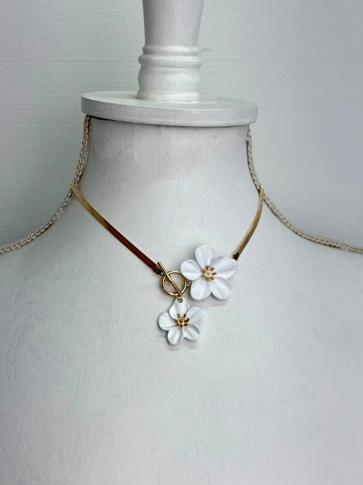 Necklace with white floral pendants on a mannequin bust against a plain background