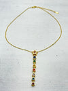 gold star necklace with multicolour gemstone drop pendant laid flat on a table