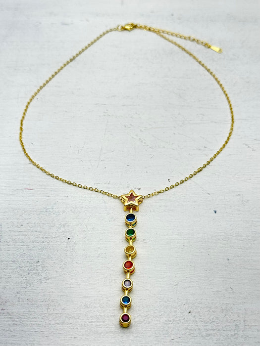 gold star necklace with multicolour gemstone drop pendant laid flat on a table