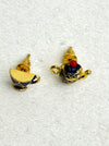 Pair of earrings shaped like teapots on a white fabric background