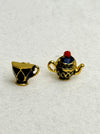 Gold teacup and teapot stud earrings on a gray background