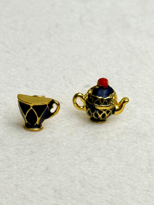 Gold teacup and teapot stud earrings on a gray background