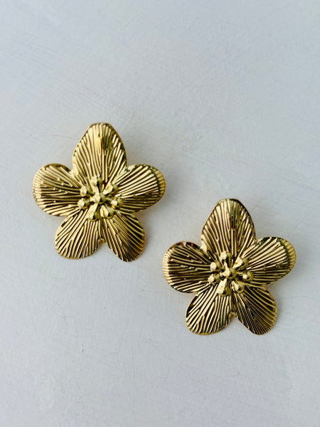 close-up of gold-tone textured flower stud earrings