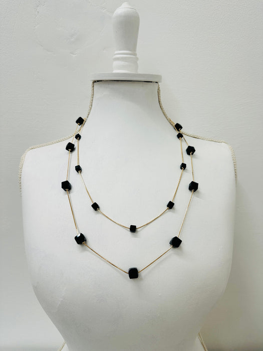 Necklace with black beads on a mannequin bust against a white background