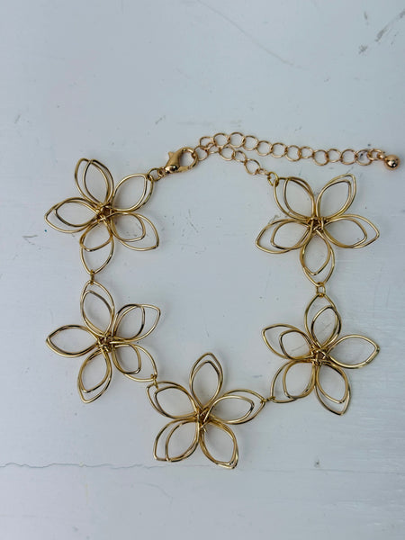 Delicate gold-tone floral bracelet with linked open-petal flower design and adjustable chain extender, displayed on a white background.