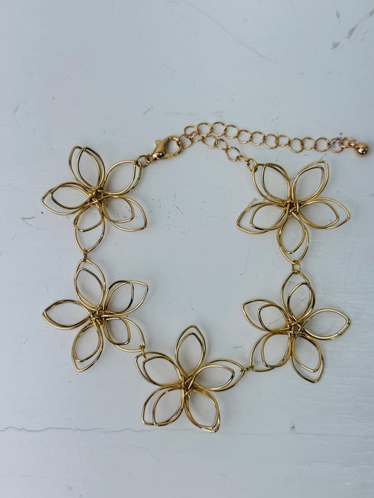 Delicate gold-tone floral bracelet with linked open-petal flower design and adjustable chain extender, displayed on a white background.